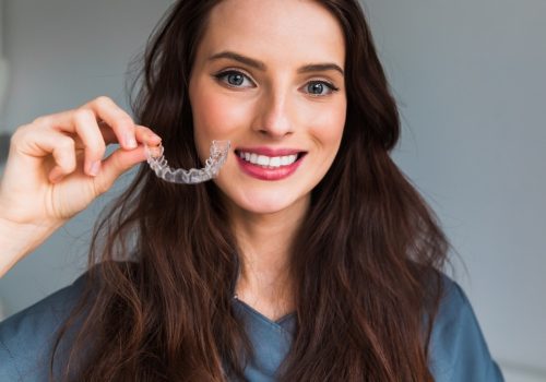 Young,Beautiful,Woman,Holding,Dental,Aligner,Orthodontic,To,Tee
